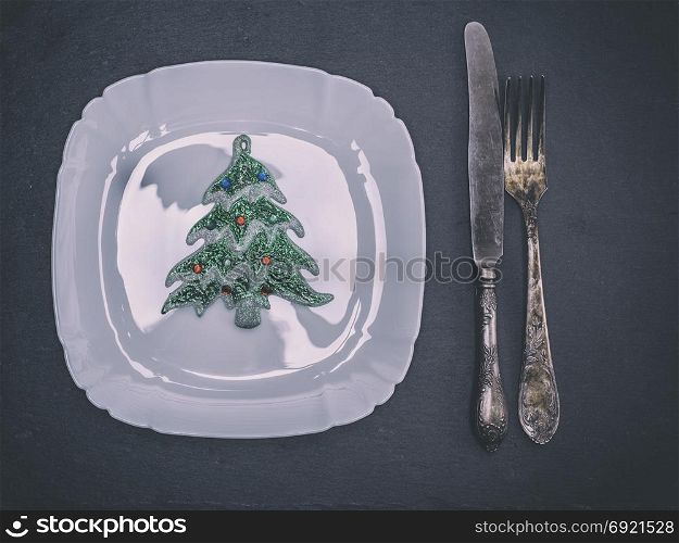white square ceramic plate with cutlery and Christmas decorations, top view
