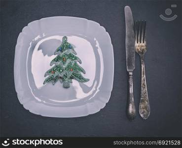 white square ceramic plate with cutlery and Christmas decorations, top view