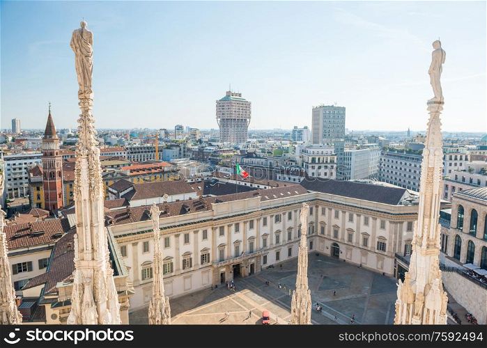 White statue on top of Duomo cathedral and view to city of Milan