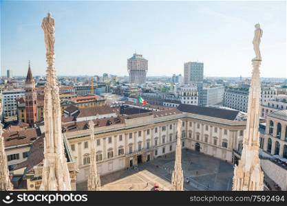 White statue on top of Duomo cathedral and view to city of Milan