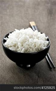 White steamed rice in asian bowl with wooden chopsticks