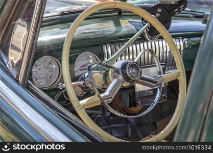White steering wheel and dashboard of an old timer car.