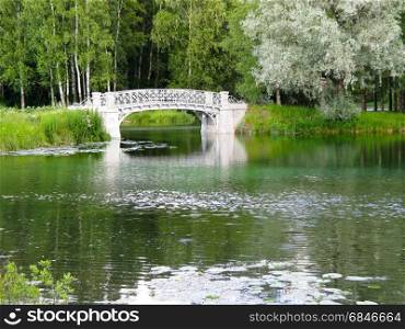 white stone bridge. white stone bridge across the river on a background of green trees
