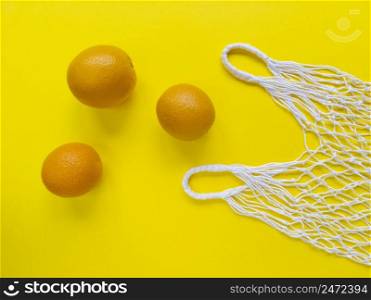 White string cotton eco bag and three oranges on yellow background. Simple flat lay. Ecology zero waste concept. Stock photography.. White string cotton eco bag and three oranges on yellow background. Simple flat lay. Ecology zero waste concept. Stock photo.