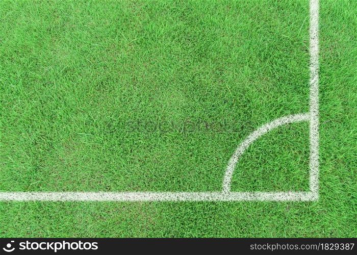 White stripe corner markings on a football field with green grass. Top view sport background.