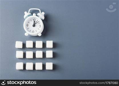 White sugar cube sweet food ingredient geometry pattern and alarm clock, studio shot isolated on a gray background, Minimal health high blood risk of diabetes and calorie intake concept