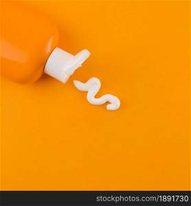 white sunscreen cream coming out orange bottle against orange backdrop. Resolution and high quality beautiful photo. white sunscreen cream coming out orange bottle against orange backdrop. High quality and resolution beautiful photo concept