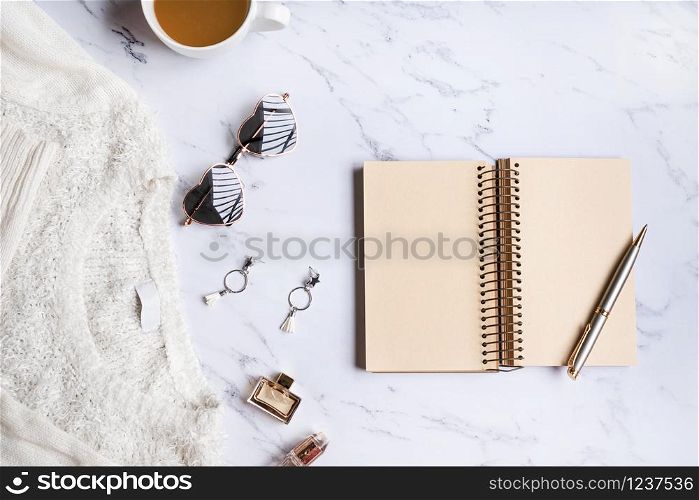 White sweater, women accessories,coffee ,notebook, smart phone on marble background top view. Women clothing. Flat lay , copy space