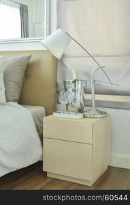 White table lamp with empty glasses and wine bottle on bed side table