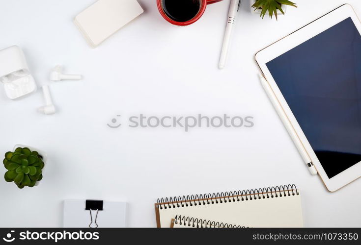 white table with electronic tablet, blank business cards, cup of coffee and wireless headphones, workplace of a freelancer or designer, top view, copy space