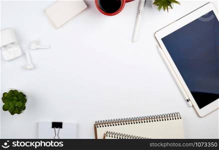 white table with electronic tablet, blank business cards, cup of coffee and wireless headphones, workplace of a freelancer or designer, top view, copy space