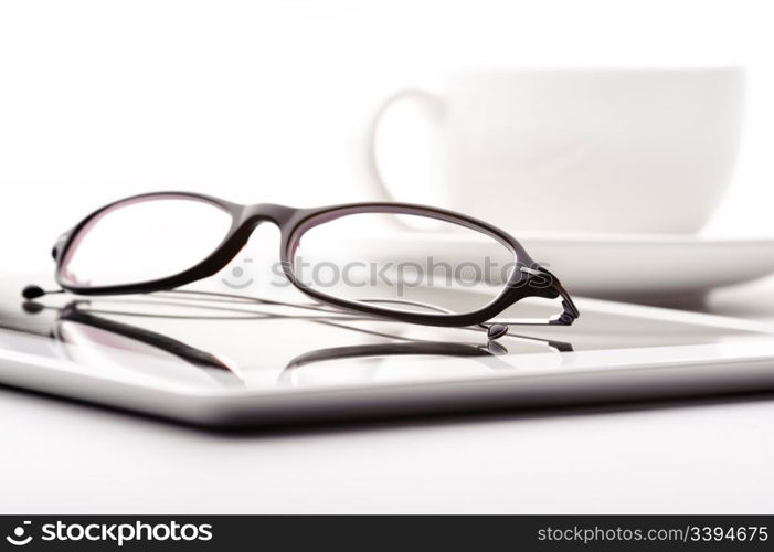 White tablet, coffee cup and glasses on a white table. Still life with white tablet, coffee cup and glasses on a white table