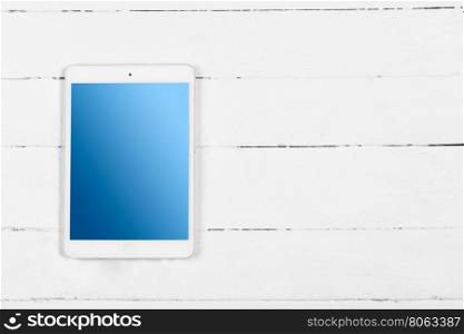 White tablet with blue screen on wooden white table. White tablet with blue screen