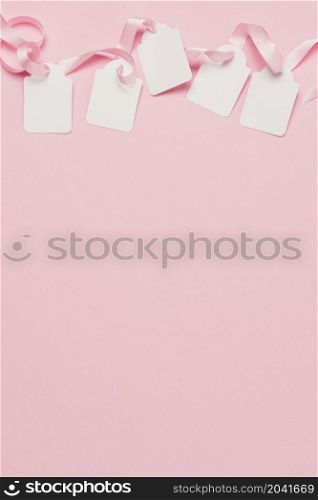 white tags pink ribbon top background with space text