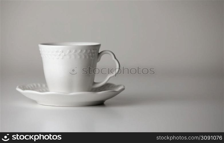 White tea cup and saucer with a pattern for drink on white background. Ceramic coffee cup or mug close up. Mockup classic porcelain utensils. copy space.. White tea cup and saucer with a pattern for drink on white background. Ceramic coffee cup or mug close up. Mockup classic porcelain utensils. copy space