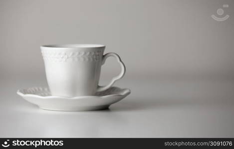 White tea cup and saucer with a pattern for drink on white background. Ceramic coffee cup or mug close up. Mockup classic porcelain utensils. copy space.. White tea cup and saucer with a pattern for drink on white background. Ceramic coffee cup or mug close up. Mockup classic porcelain utensils. copy space