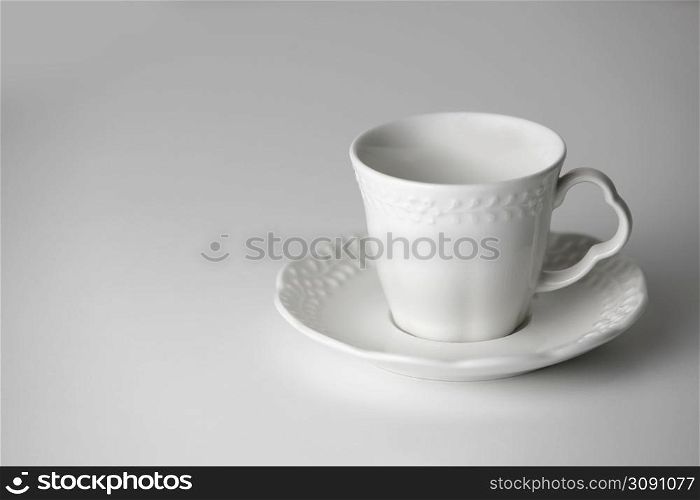 White tea cup and saucer with a pattern for drink on white background. Ceramic coffee cup or mug close up. Mockup classic porcelain utensils. copy space.. White tea cup and saucer with a pattern for drink on white background. Ceramic coffee cup or mug close up. Mockup classic porcelain utensils. copy space
