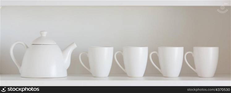 white teapot and cups on the shelf