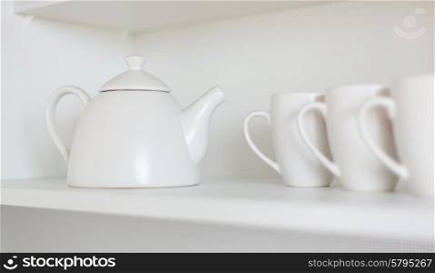 white teapot and cups on the shelf