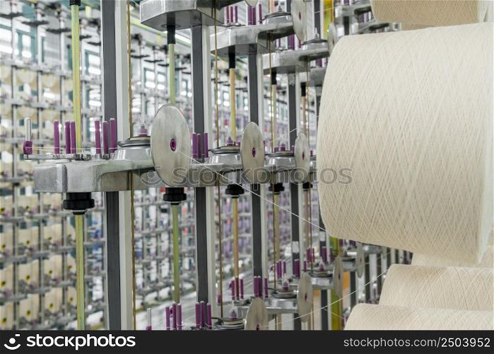 white textile yarn on the warping machine. machinery and equipment in a textile factory. textile yarn processing shop