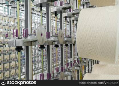 white textile yarn on the warping machine. machinery and equipment in a textile factory. textile yarn processing shop