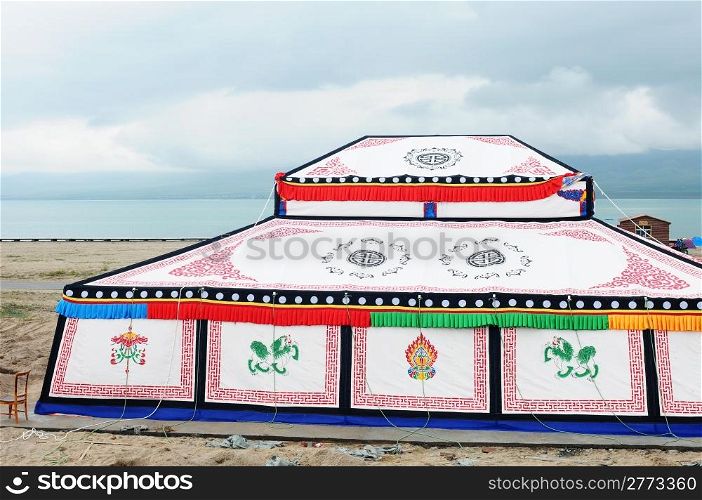 White Tibetan tent with colorful paintings at the lakeside