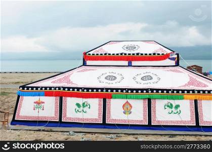 White Tibetan tent with colorful paintings at the lakeside
