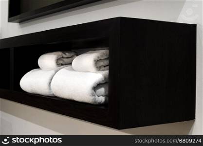 white towels on wooden shelf in bedroom