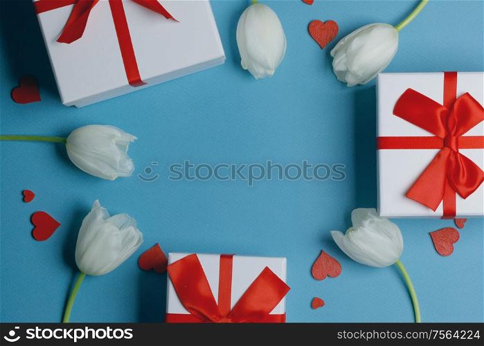 White tulip flowers gifts red hearts and gifts composition on blue background top view with copy space. Valentine&rsquo;s day, birthday, wedding, Mother&rsquo;s day concept. Copy space. White tulips hearts gifts card