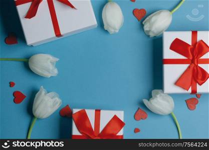 White tulip flowers gifts red hearts and gifts composition on blue background top view with copy space. Valentine&rsquo;s day, birthday, wedding, Mother&rsquo;s day concept. Copy space. White tulips hearts gifts card