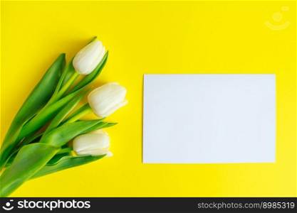 White tulips bouquet and greeting card on yellow background. Spring holidays concept, mockup.. White tulips bouquet and greeting card on a yellow background. Spring holidays concept, mockup.