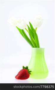 white tulips in a vase and strawberries isolated on white