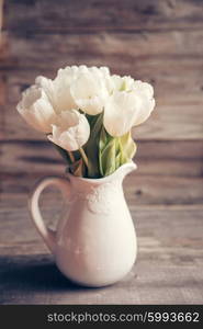 White tulips in a vase in pastel colors on rustic background