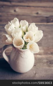 White tulips in a vase in pastel colors on rustic background
