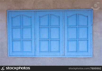 White wall with window with closed bluewooden shutters