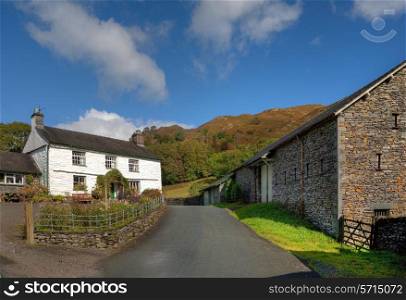 White-washed farmhouse and barns near Loughrigg Tarn, Cumbria, England.