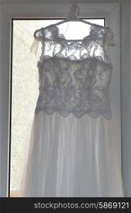 white wedding dress hangs on hanger in room