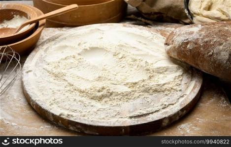 white wheat flour and wooden rolling pin on board, baking ingredients, close up