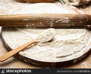 white wheat flour in a wooden spoon, top view, close up