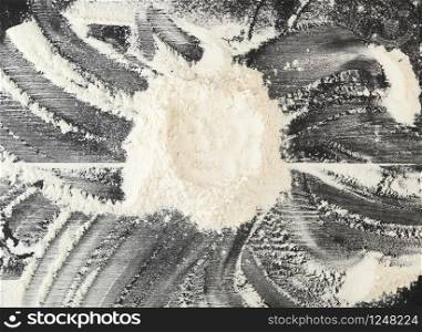 white wheat flour scattered on a black table, in the middle a circle figure, top view