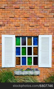 White window and colorful glass on orange brick wall