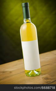 White wine bottle on wooden table over dark green / yellow background