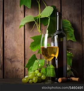 White wine, grapes, corkscrew, and bottle on wood background closeup