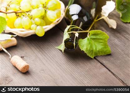 White wine, grapes, corkscrew, and cork on wood background closeup