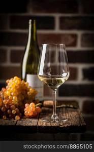 White wine in a glass with fall grapes, dark wooden background. White wine in a glass
