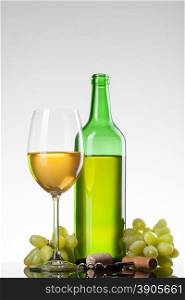 White wine in glass with grape and bottle isolated on white