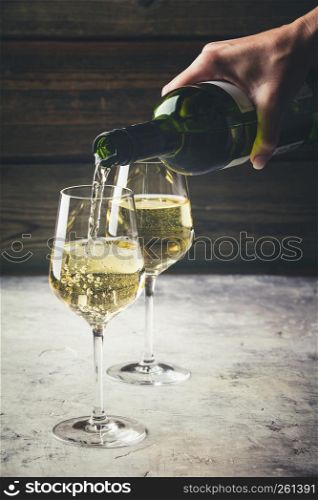 White wine pouring into glasses on the stone background. White wine pouring into glasses, close up