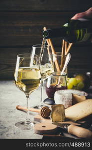 White wine pouring into glasses with charcuterie assortment on the stone background. White wine pouring into glasses with charcuterie assortment