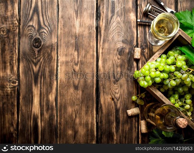 White wine with a box full of grapes. On a wooden table.. White wine with a box full of grapes.