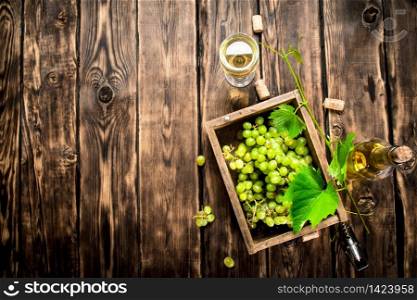 White wine with a box full of grapes. On a wooden table.. White wine with a box full of grapes.